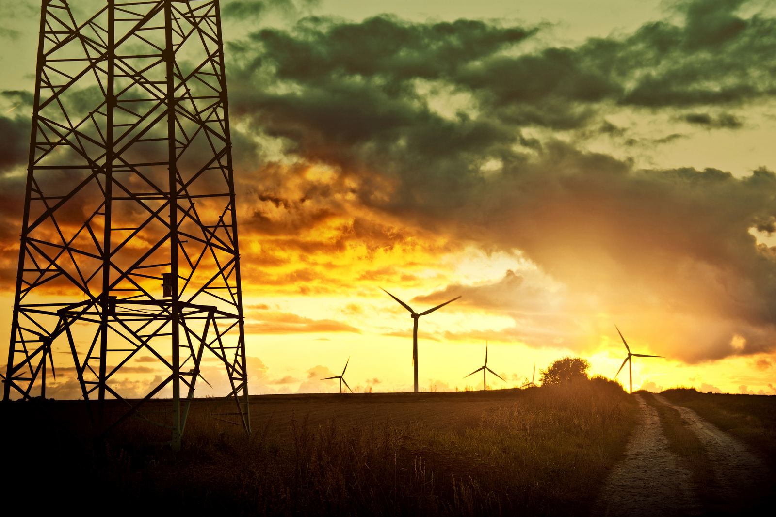 Transmission tower and wind turbines at sunset